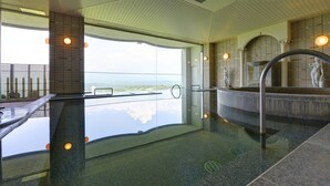 A modern indoor swimming pool with a clear view of the landscape, a statue, and a stone fountain. - Hotel Azalea (Tsu)