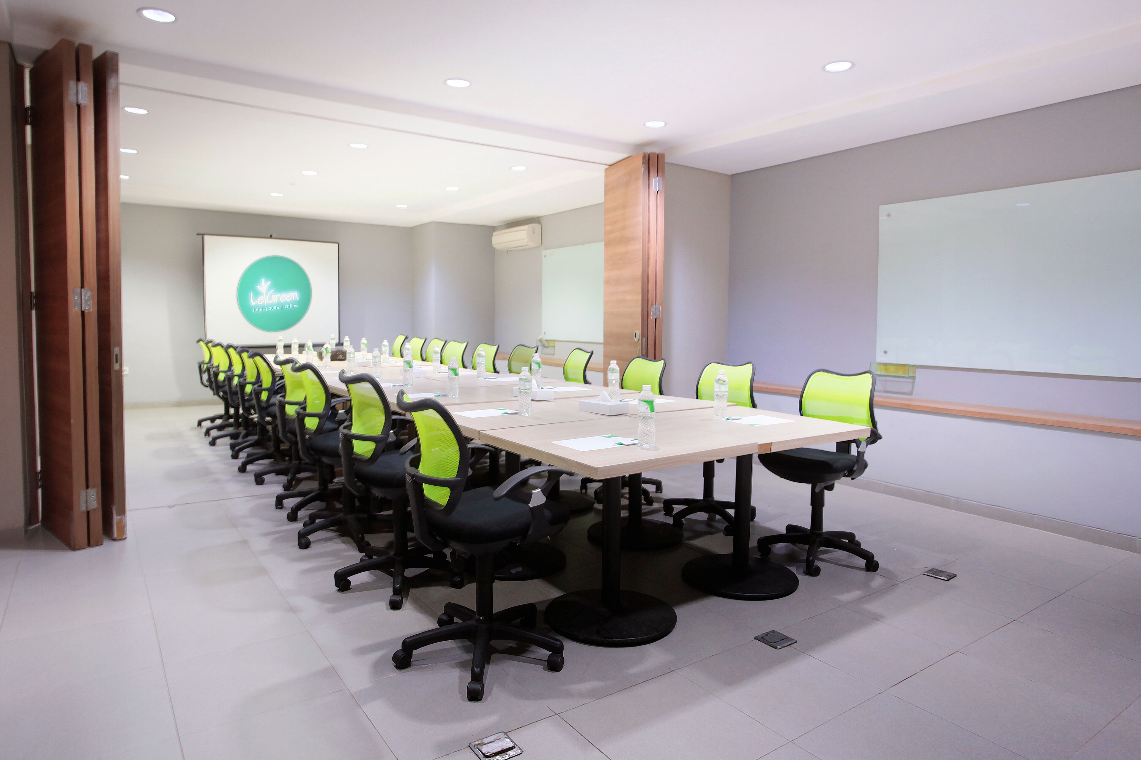 A conference room with a long table, chairs, a projector screen, and a whiteboard.