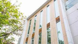 A modern building with vertical wooden panels and large windows. - LeGreen Suite Kuningan (Jakarta)