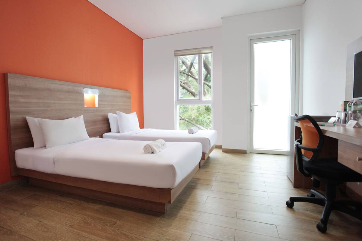 A hotel room with two beds, a desk, and a chair.