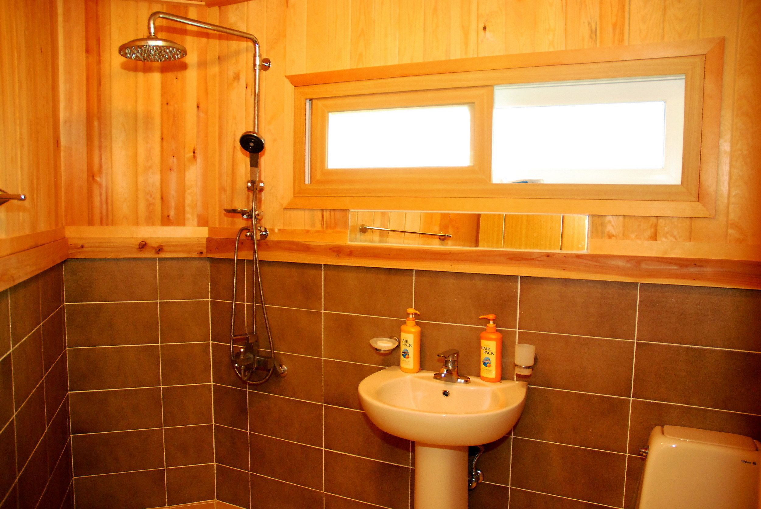 A bathroom with a wooden interior, a sink with toiletries, and a shower.
