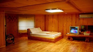 Une pièce en bois avec un lit, une télévision et une petite table sur laquelle se trouvent des fruits.