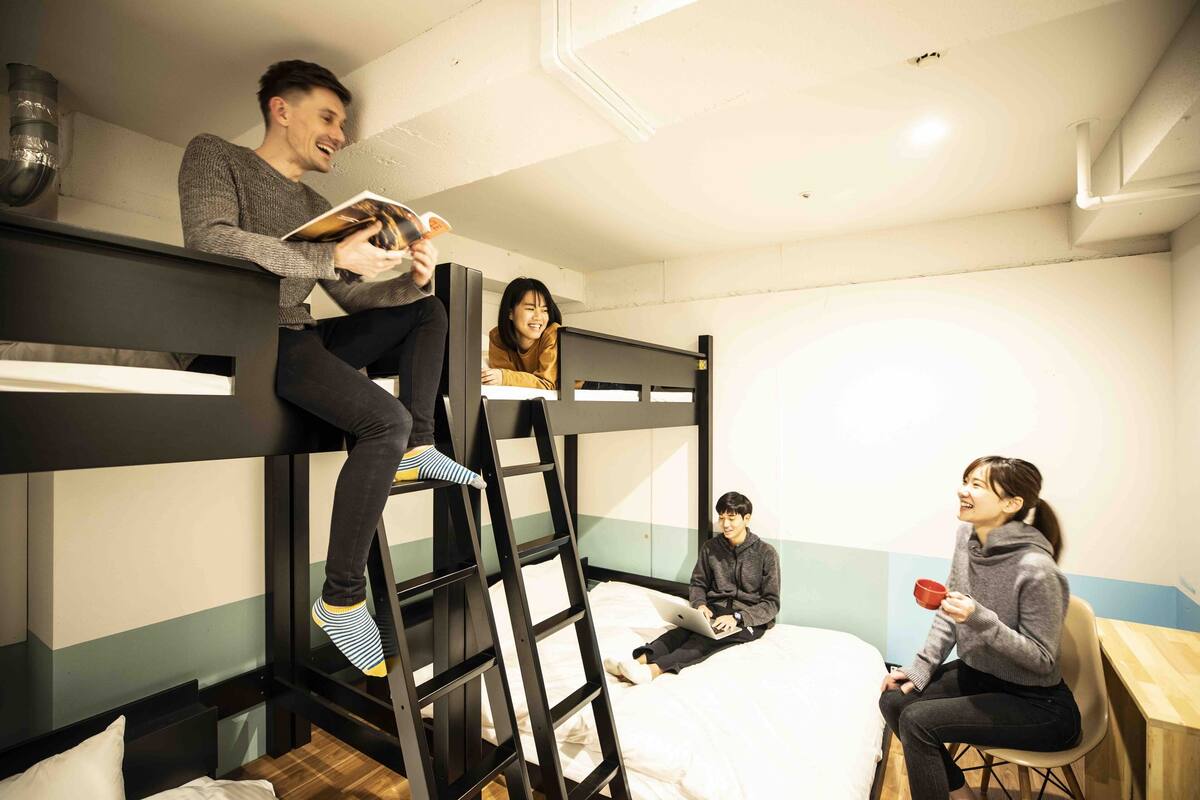 A bunk bed room with a ladder, a desk, and a chair.