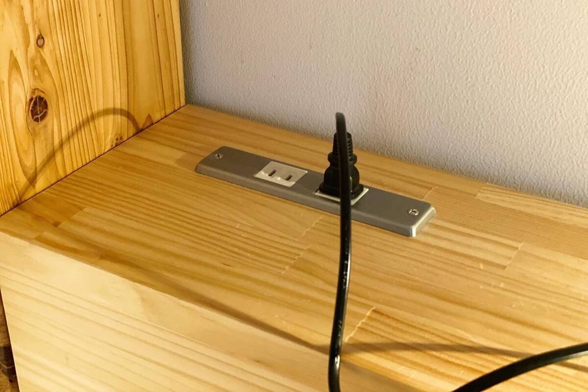 A wooden table with a power strip and a black cable plugged in.