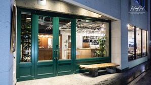 A restaurant with a green facade, a reception area, and a wooden bench outside. - HafH Fukuoka THE LIFE - Hostel (Fukuoka)