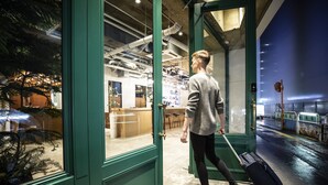 A person with a suitcase entering a building through a green door. - HafH Fukuoka THE LIFE - Hostel (Fukuoka)