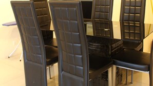 A dining area with a glass table surrounded by four black chairs with cushioned backs. - Peaceful Service Suites at Taragon Puteri Bintang (Kuala Lumpur)
