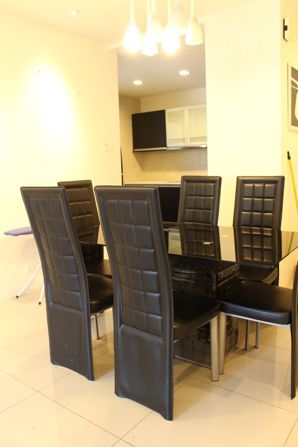 A dining area with a glass table surrounded by four black chairs with cushioned backs.