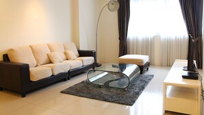 A modern living room with a sofa, a glass coffee table, a side table, and a floor lamp. - Peaceful Service Suites at Taragon Puteri Bintang (Kuala Lumpur)