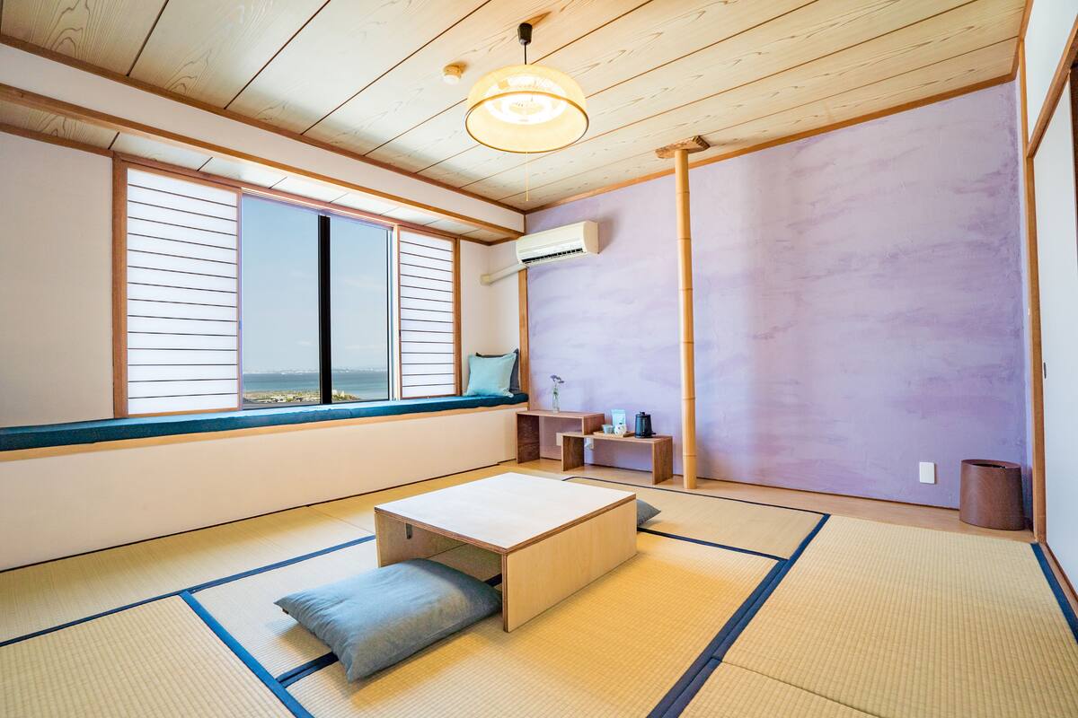 Una habitació tradicional japonesa amb sòls de tatami, una taula de fusta baixa, vista a través de pantalles shoji i una paret de bambú.