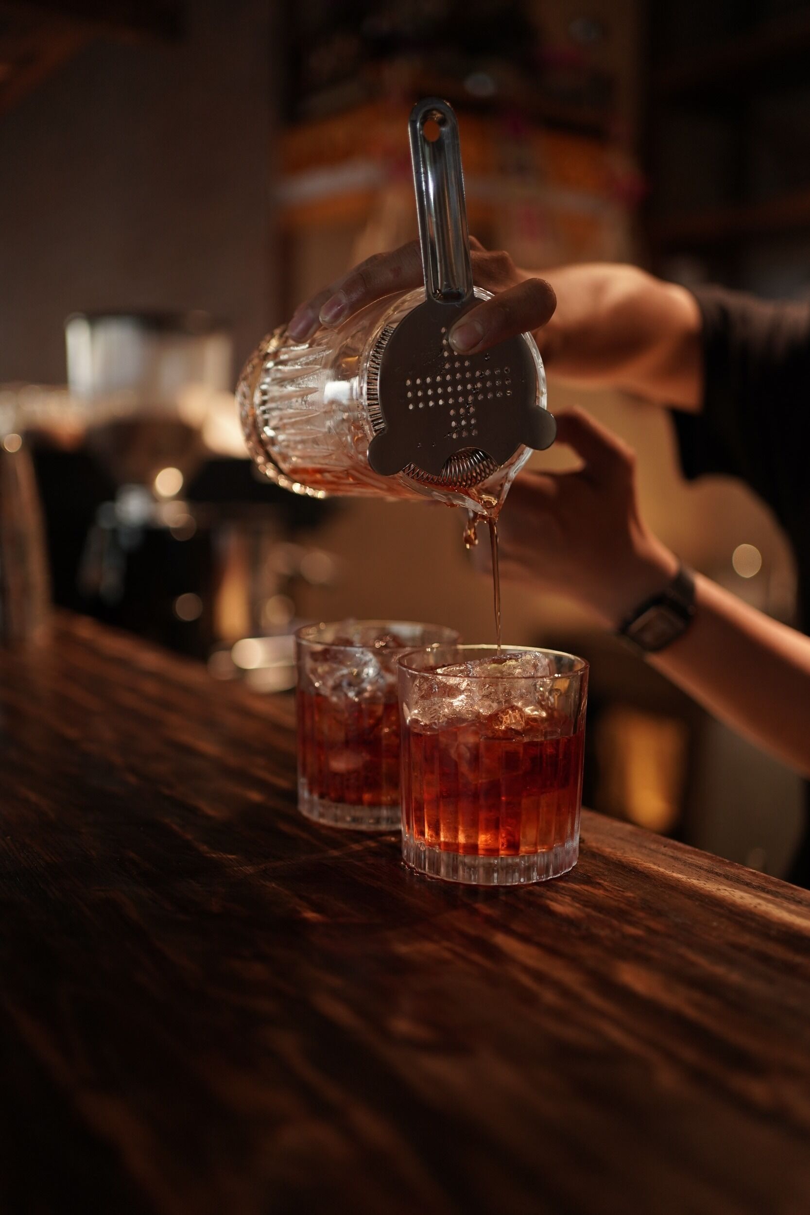 A person pouring a drink from a shaker into a glass.
