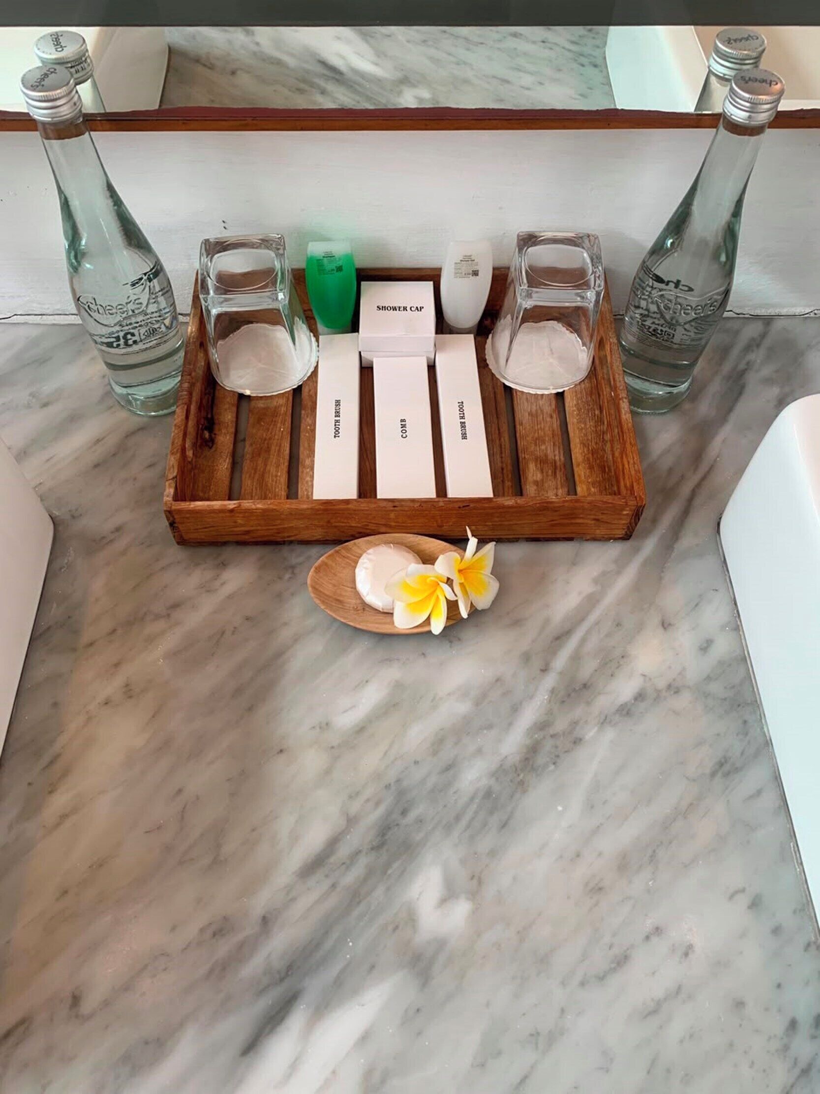 A wooden tray with toiletries and a decorative item on a marble countertop.