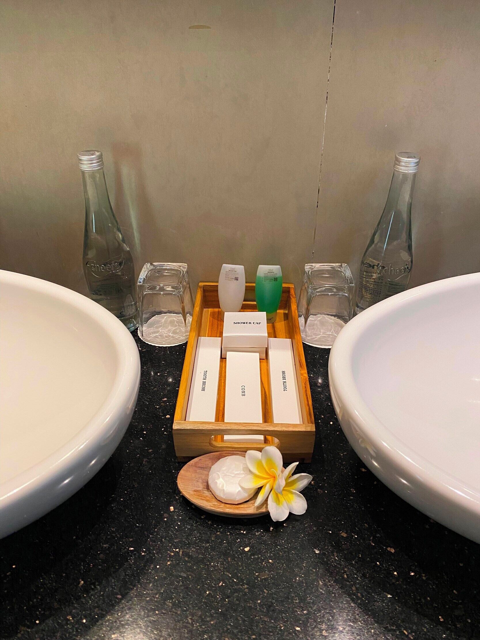 A bathroom with two sinks, a wooden tray with toiletries, and a decorative flower.