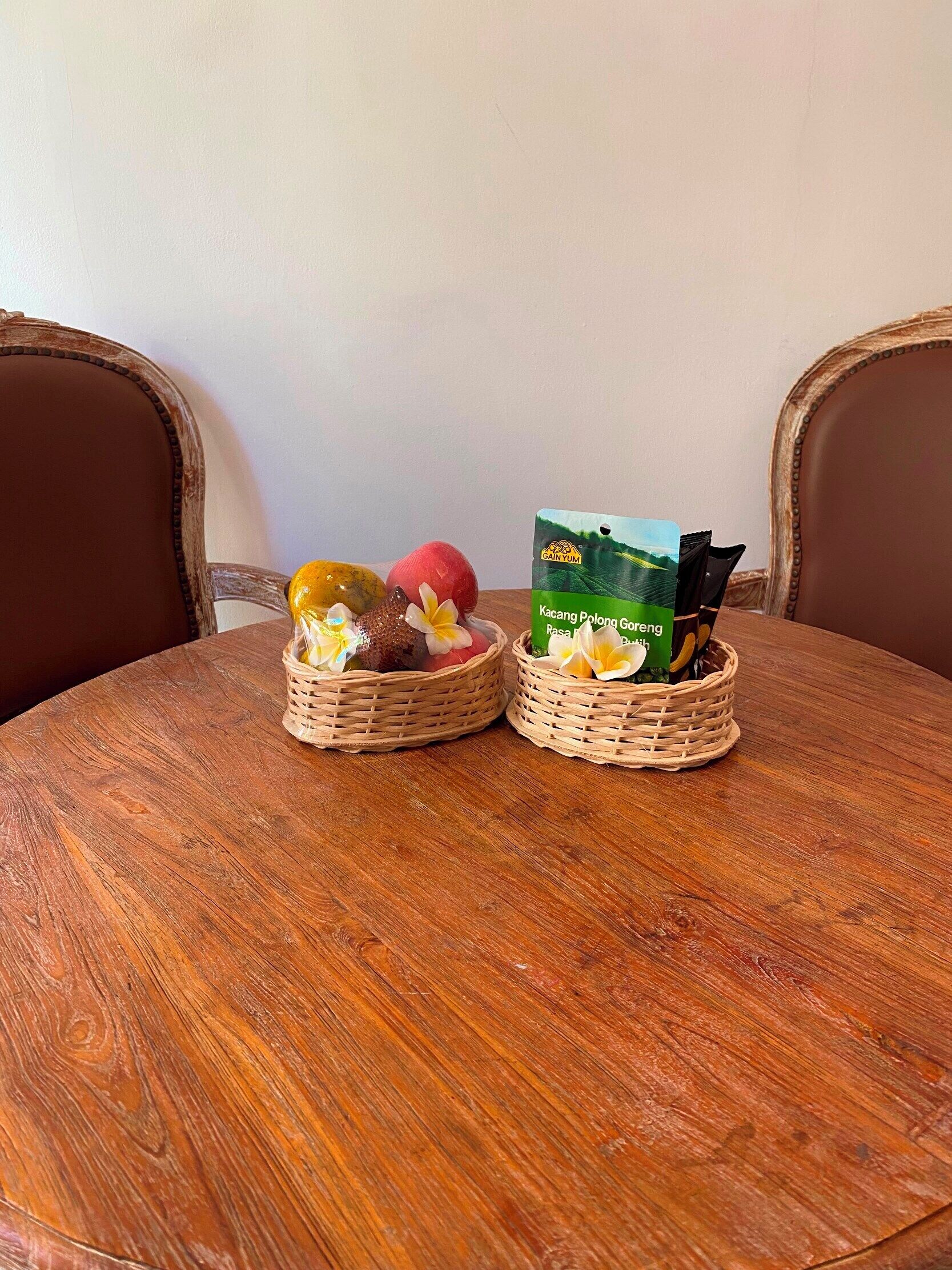 Two woven baskets on a round wooden table with a white wall in the background.