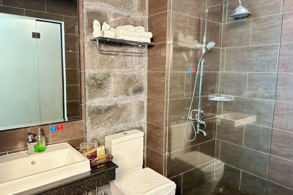 Un baño con ducha, inodoro, lavamanos y espejo.