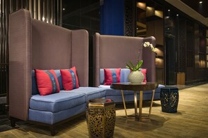 A modern lounge area with a blue sofa set, decorative pillows, a small round table with a vase, and two ornate side tables. - Aliana Boutique Sapa Hotel & Spa (Sa Pa)