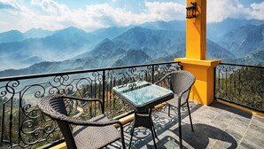 Un balcón con mesa y sillas, con vistas a un paisaje montañoso.