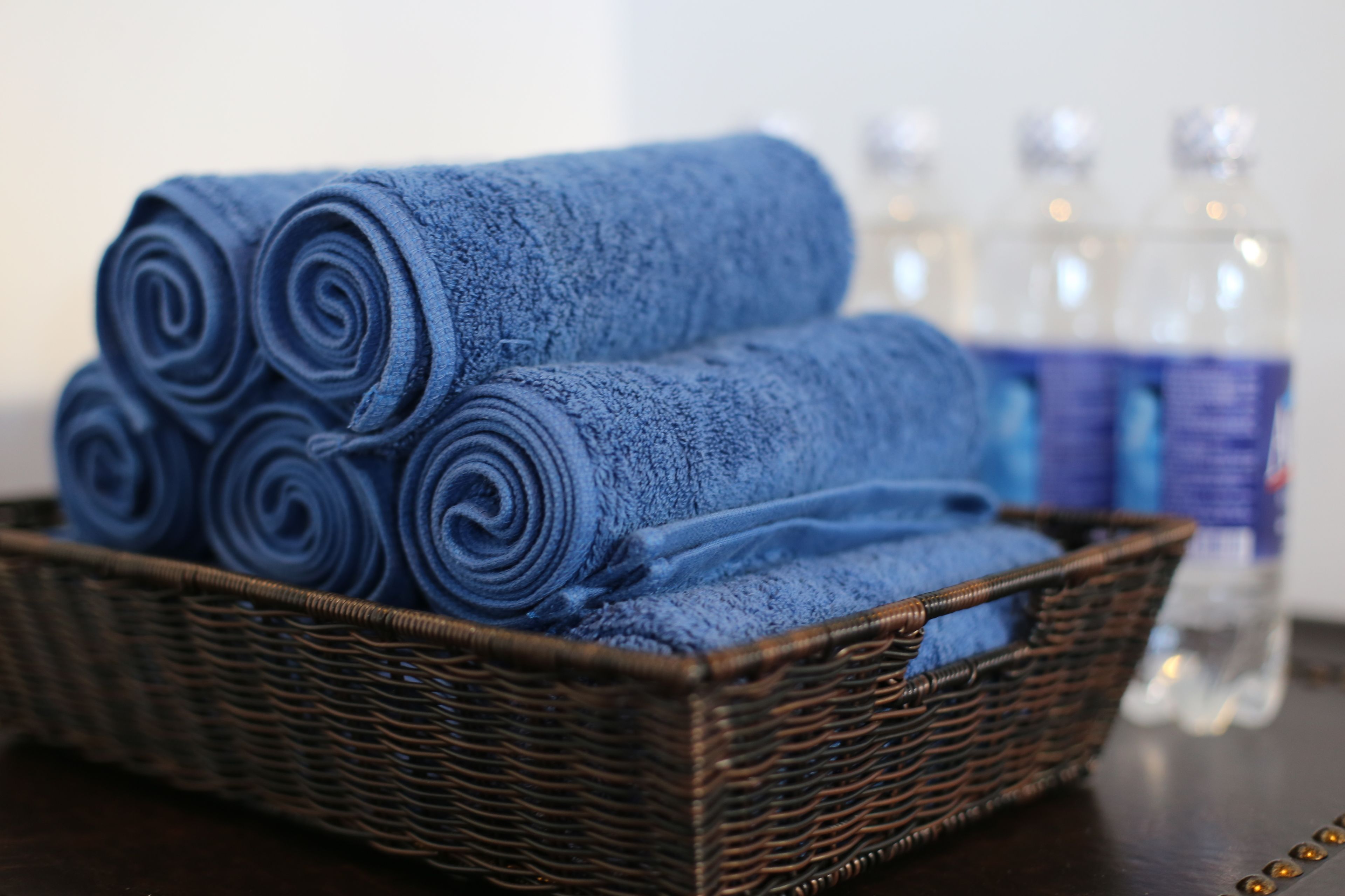 A wicker basket with rolled blue towels and clear water bottles in the background.