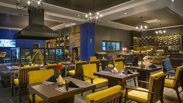 Un restaurante con sillas amarillas, mesas oscuras y un extractor grande y negro.