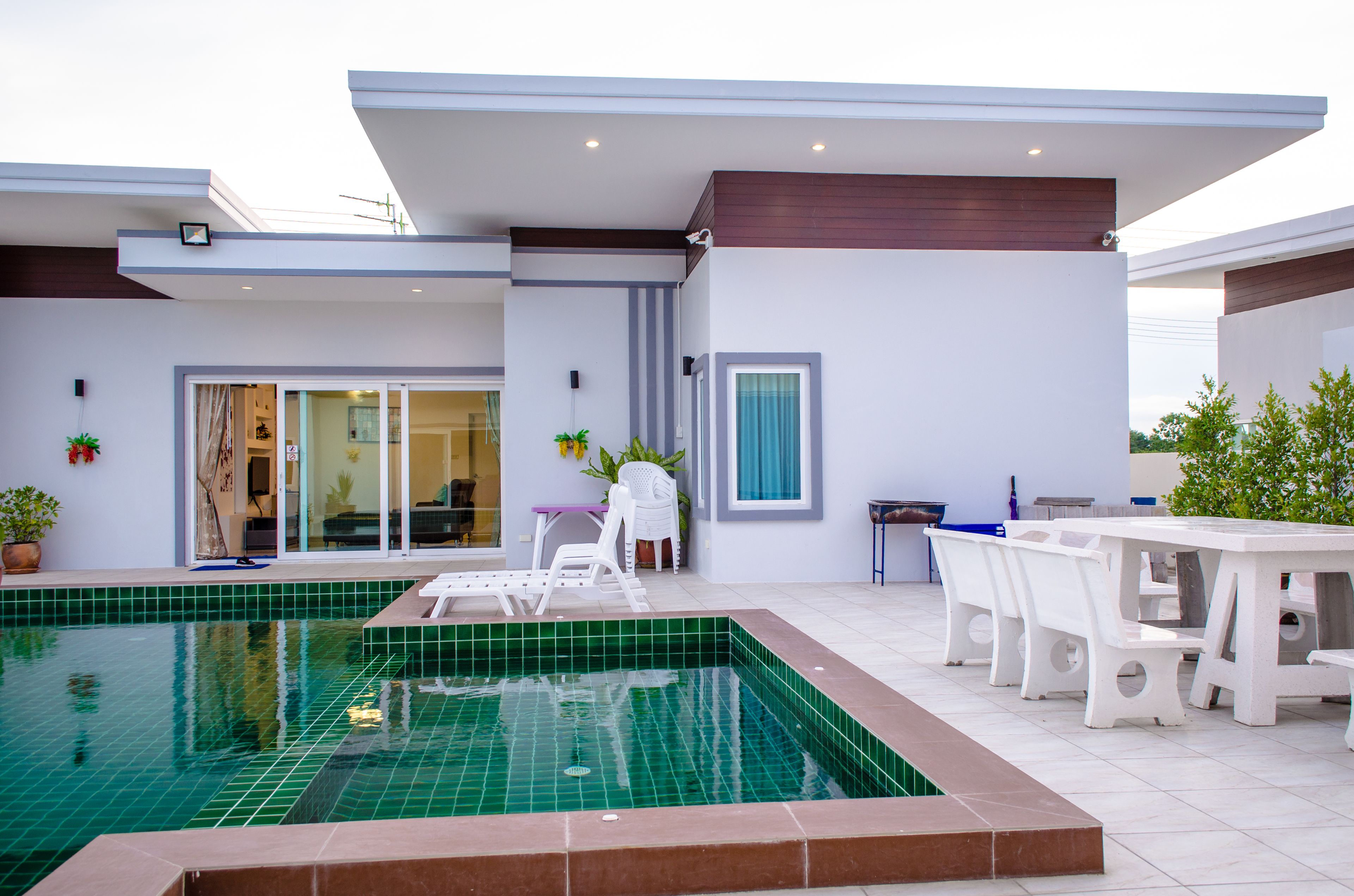 A modern house with a swimming pool, outdoor seating, and a patio area.