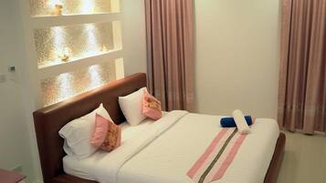 A neatly made bed with a white and pink striped bedspread, a brown headboard, and a small nightstand with a lamp.