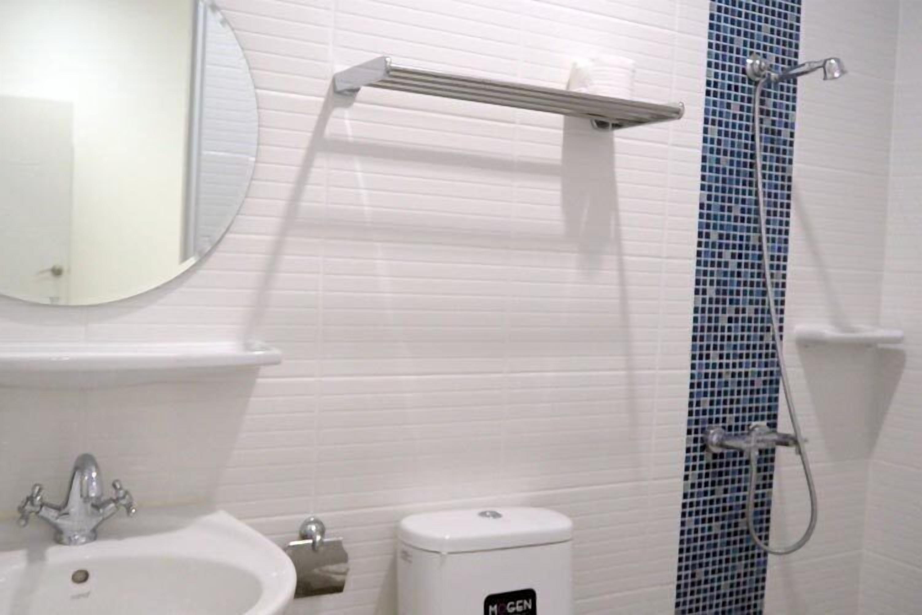 Une salle de bain avec un lavabo blanc, un miroir et une douche aux carreaux de mosaïque bleus.