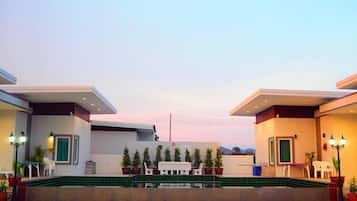 A modern hotel with a rooftop pool area, outdoor seating, and potted plants.