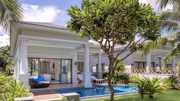 A poolside area with a lounge chair, a small pool, and a tree.