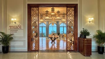 A hotel lobby with a reception desk, a decorative entrance, and a view of the outdoors.