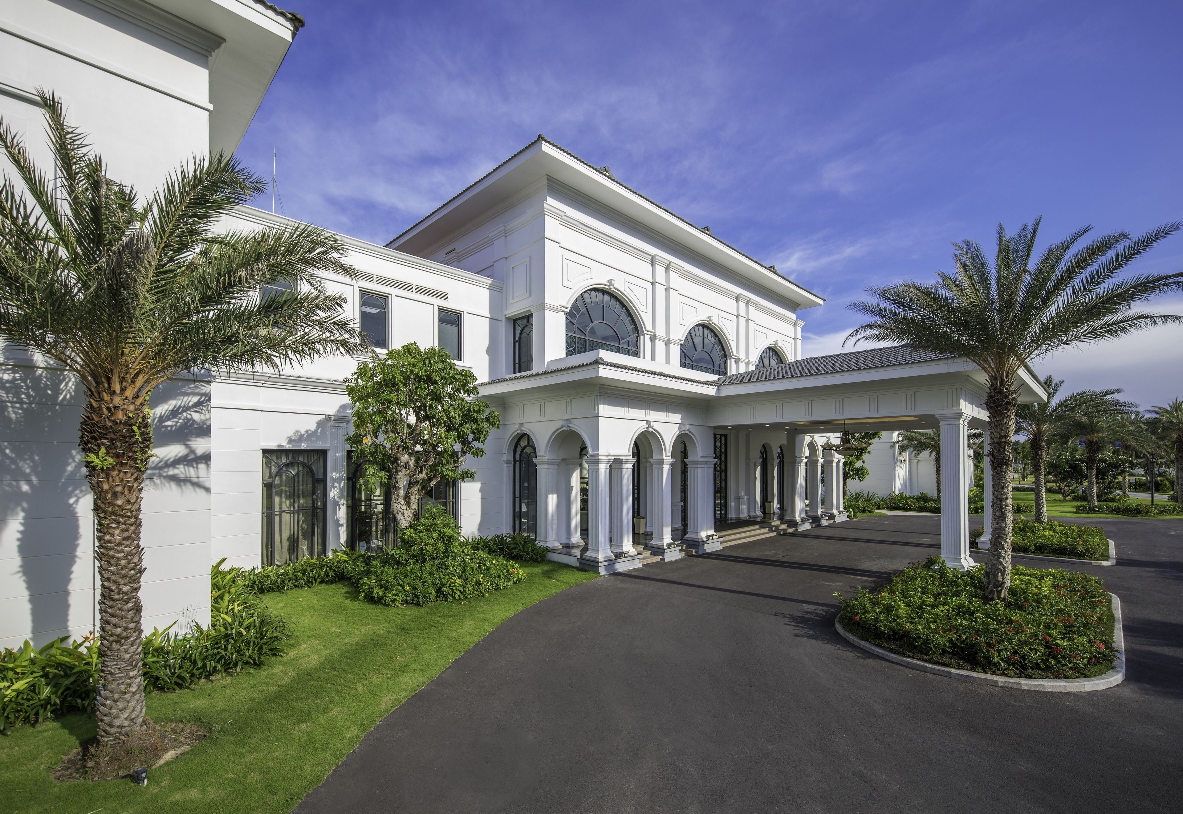 A large, white building with a symmetrical facade, arched windows, and a covered entrance area.