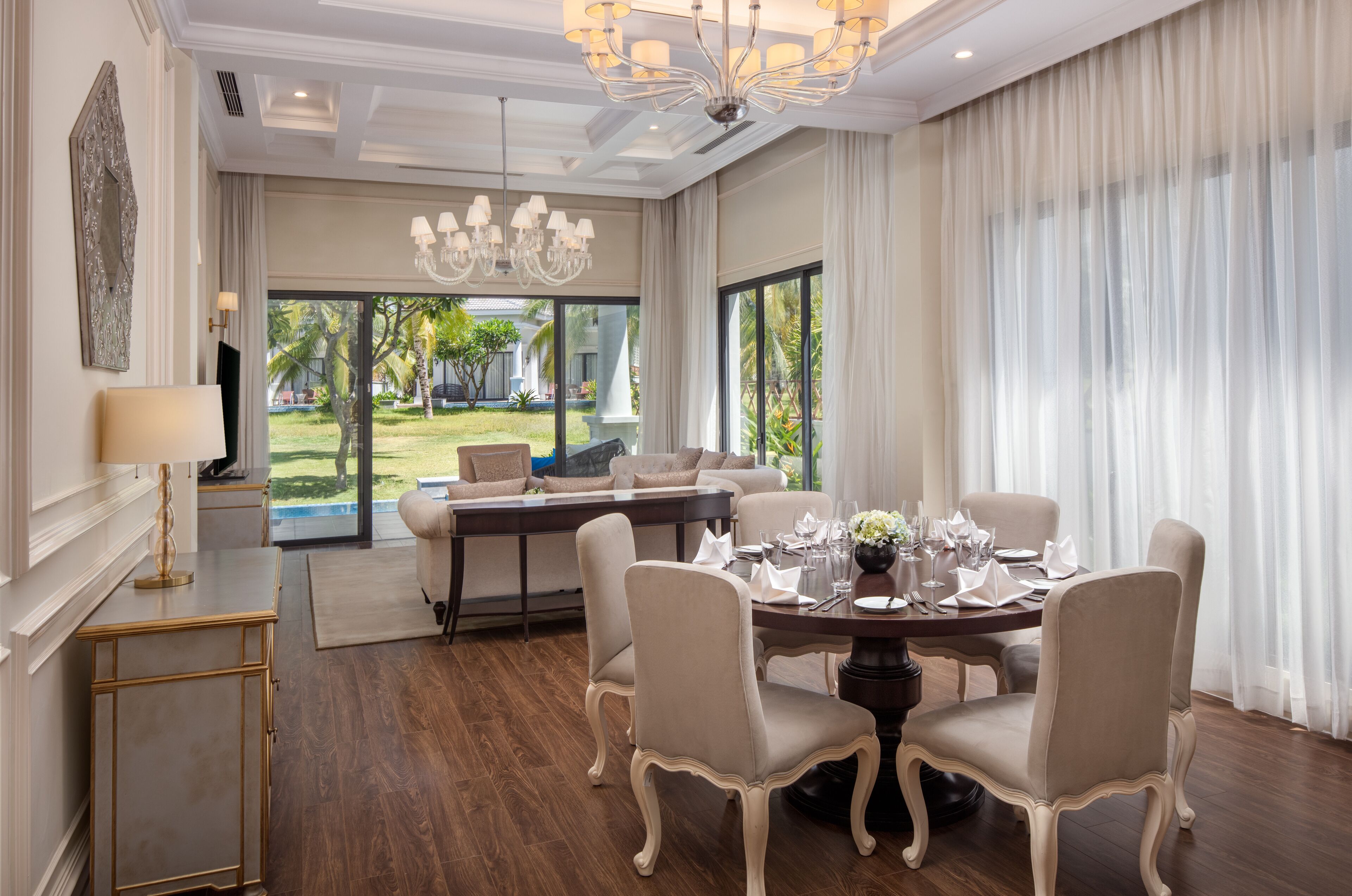 A dining area with a round table set for six, surrounded by six chairs.
