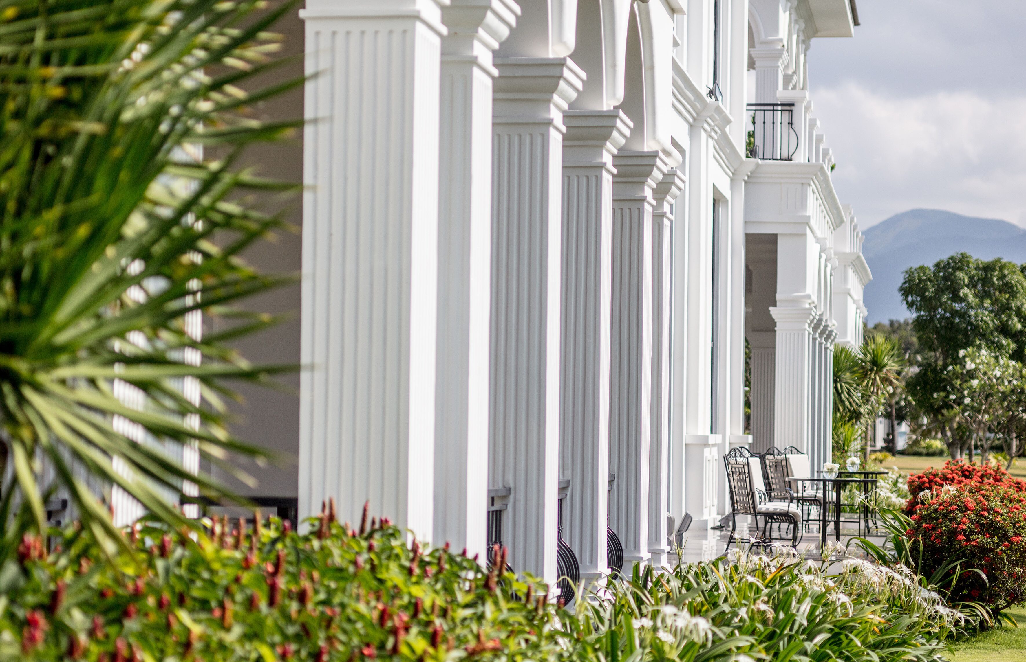 A white building with columns, a balcony, and outdoor seating.