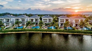 Una hilera de casas modernas con piscina frente a un cielo al atardecer.