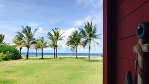 A grassy area with palm trees and a view of the ocean. - Ocean Front Campgrounds (Ngwe Saung)