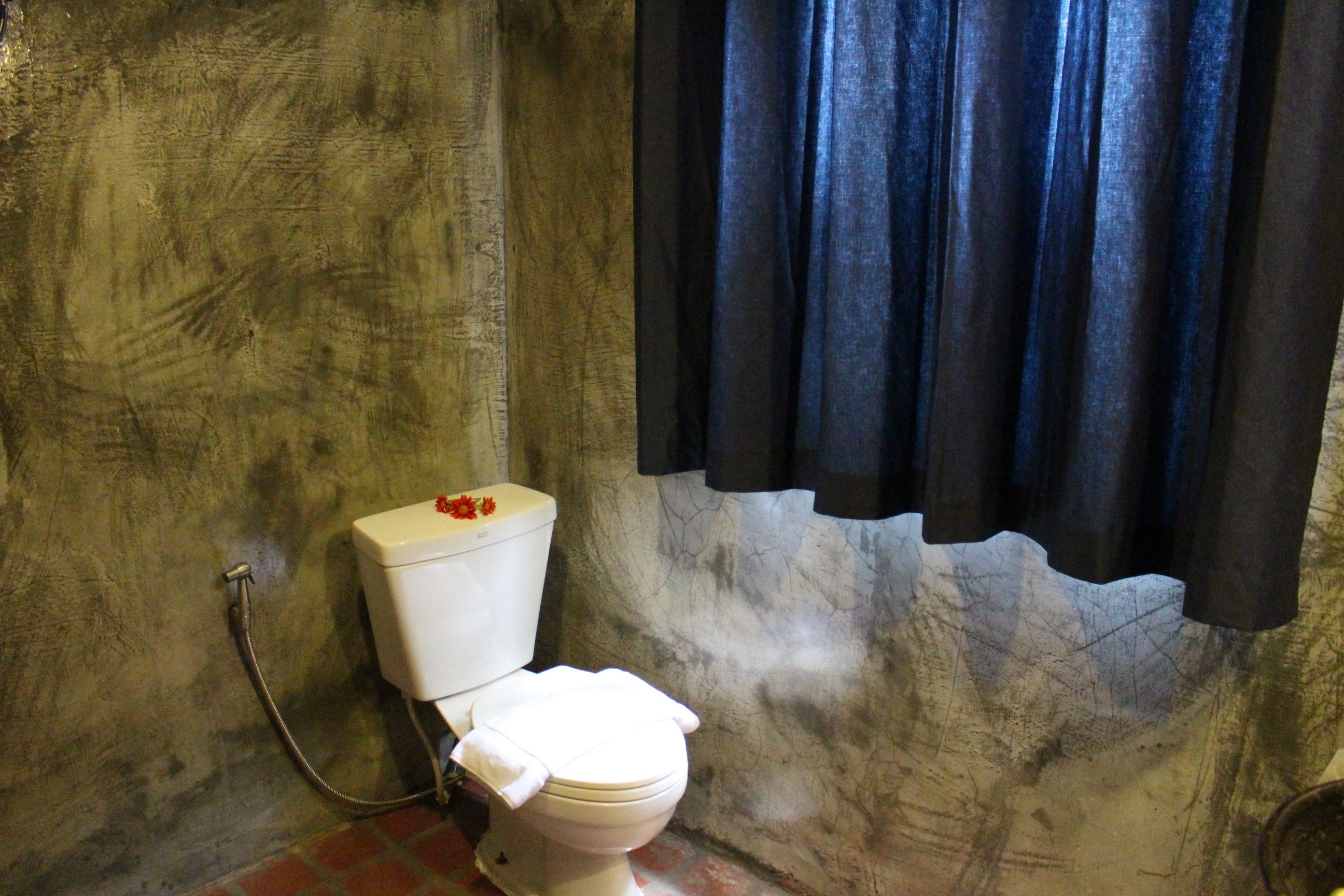 Un baño con inodoro blanco, ducha y cortina.