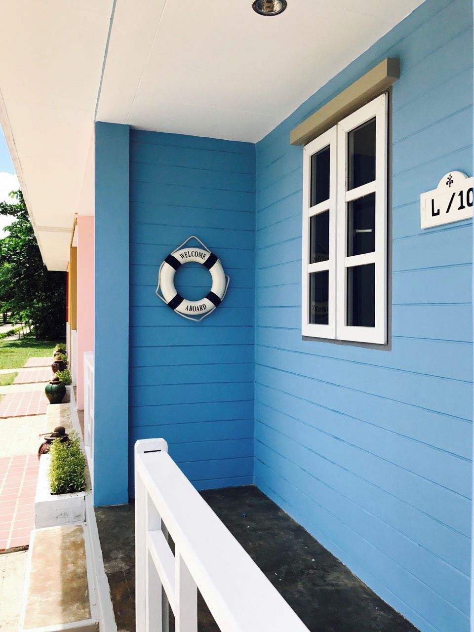 Pared exterior azul con una ventana blanca y un letrero de boya salvavidas.