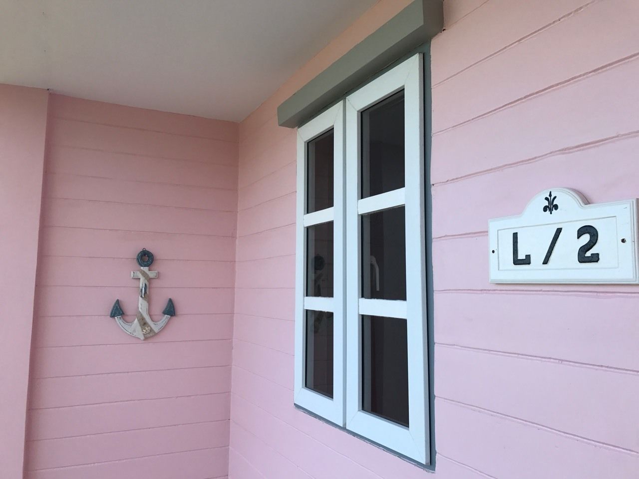 A pink building with a white window and a sign reading "L/2".