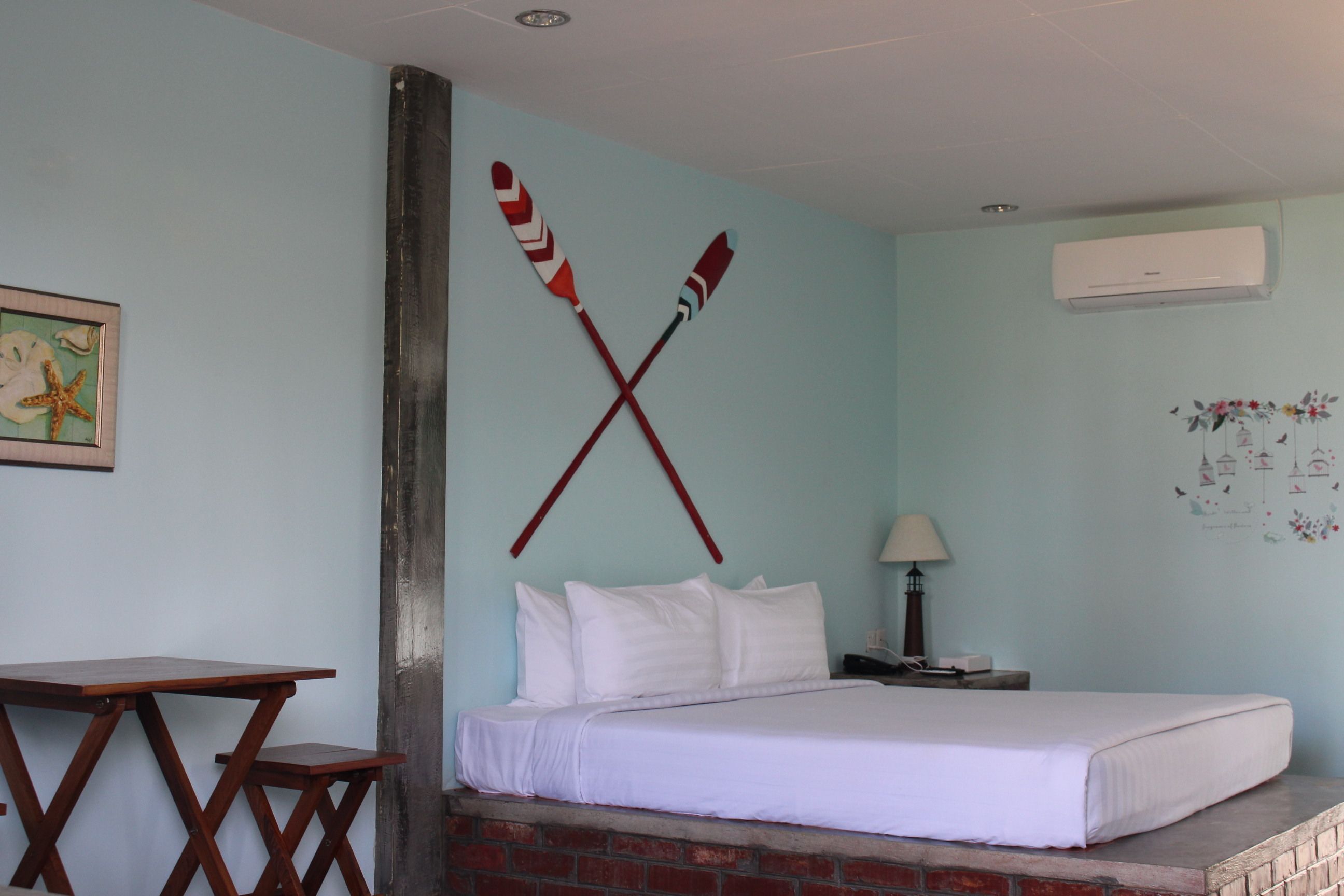A bedroom with a bed, a wooden table, and a wall-mounted air conditioner.