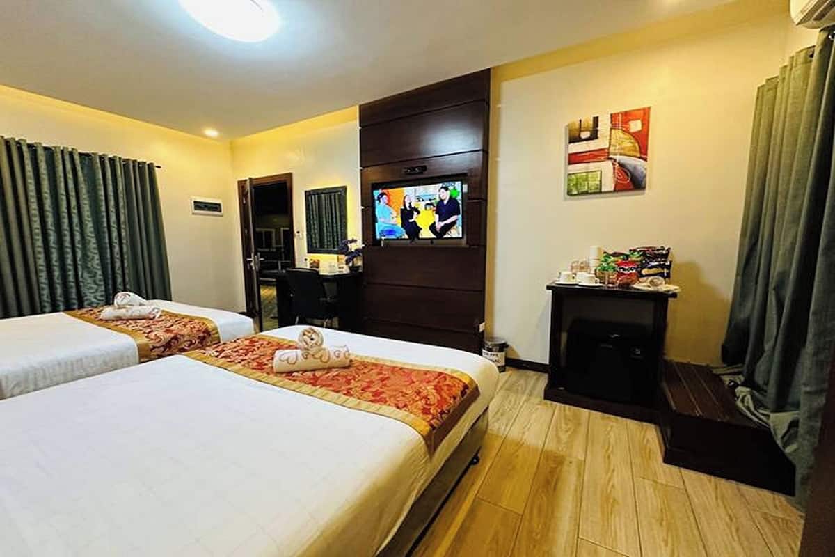 A hotel room with two beds, a TV, a desk, and a small seating area.