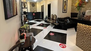 Un hall d’hôtel avec un sol à carreaux, des espaces aménagés avec des sièges et un comptoir d’accueil.