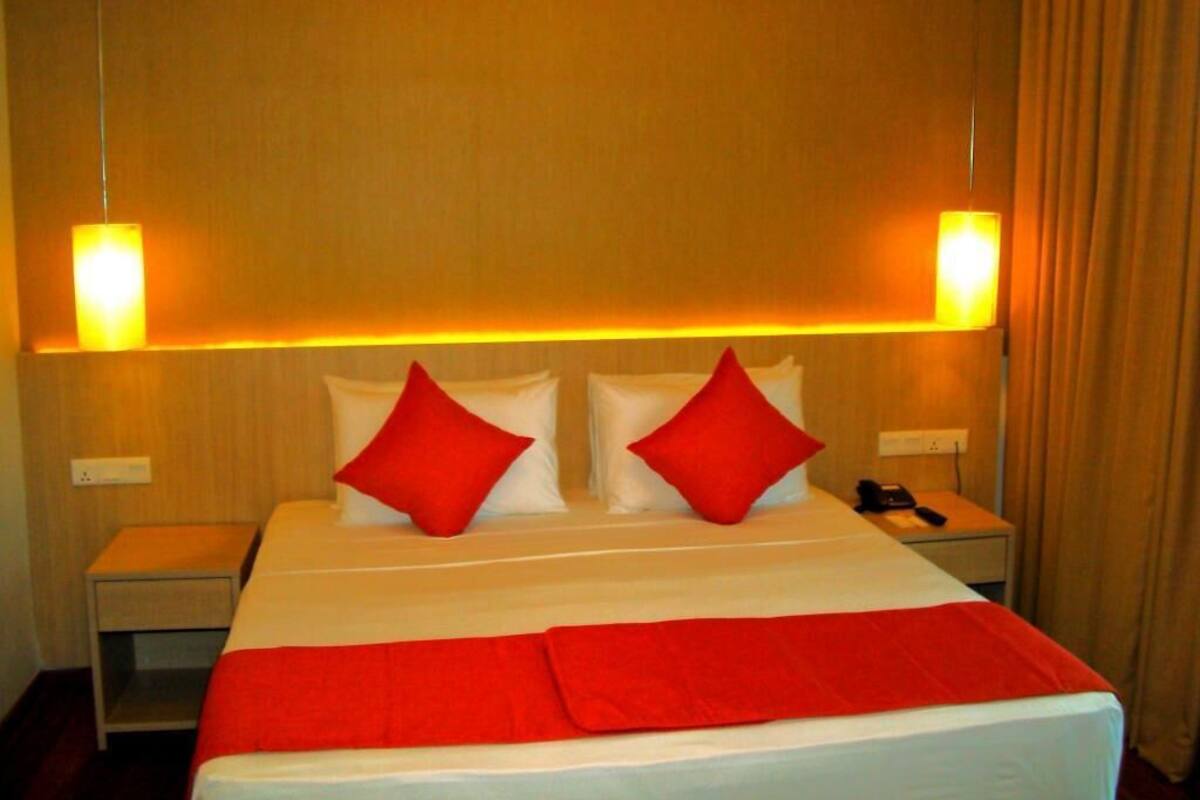 A hotel room with a bed, two nightstands, and a telephone.