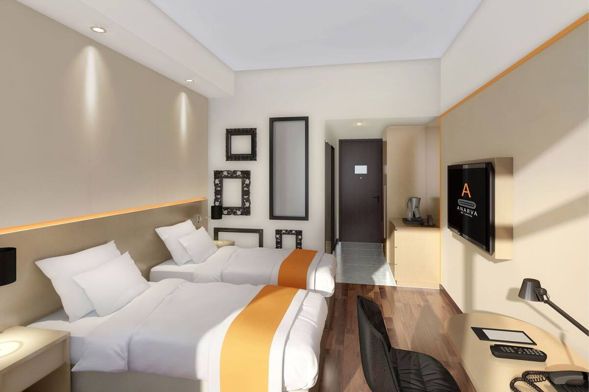 A hotel room with two beds, a desk, a TV, a phone, and a mirror.