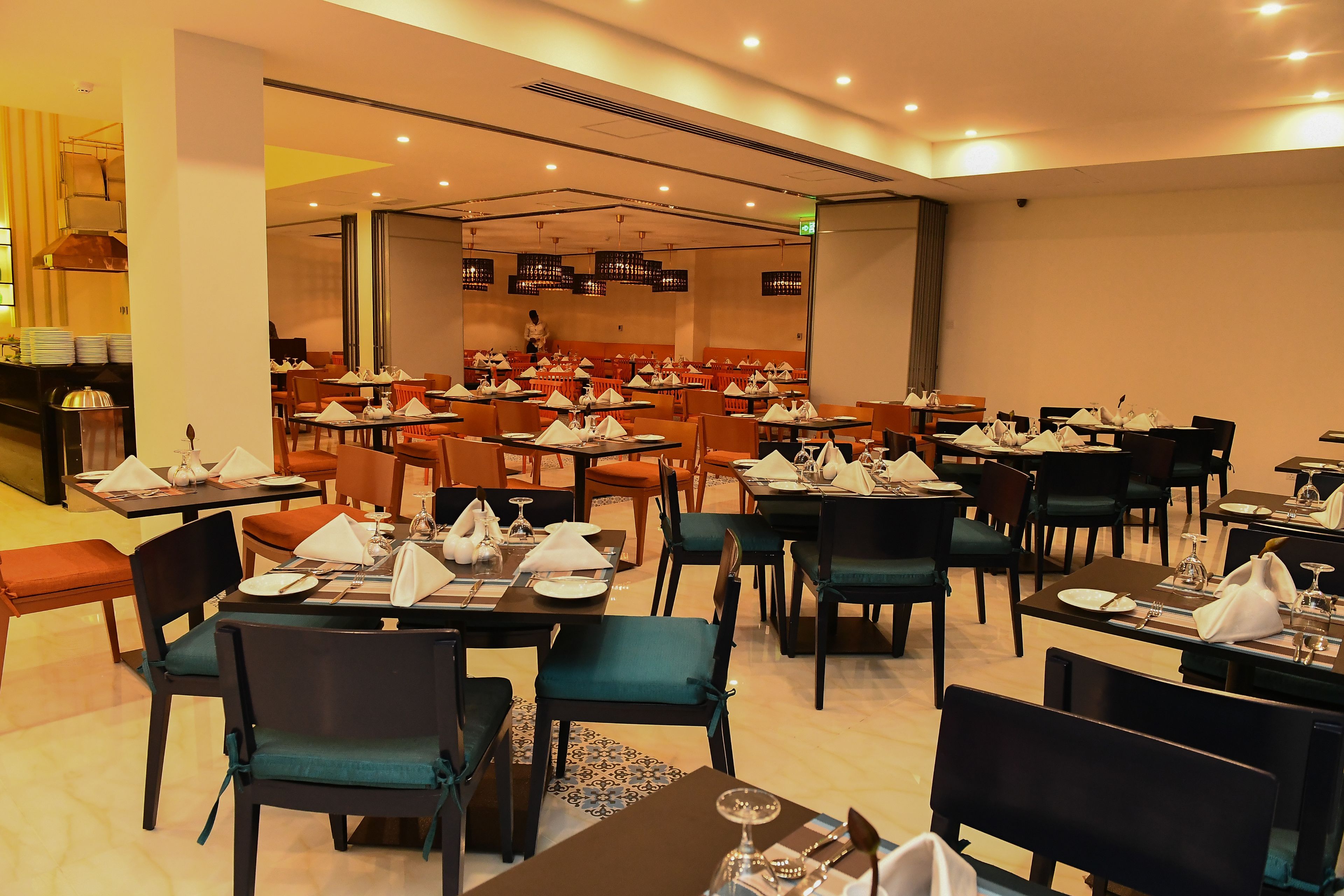 A spacious restaurant with multiple tables and chairs, each set with white napkins and silverware.
