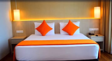 A hotel room with a large bed, two nightstands, a telephone, and a lamp on each side.