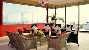 Habitación de hotel moderno en un rascacielos, con muebles de mimbre, ventanas amplias y vista a la ciudad.