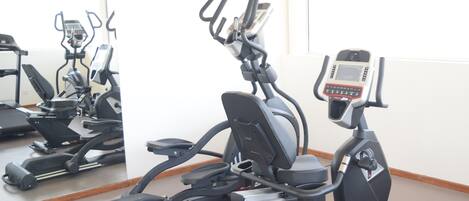 Een fitnessruimte met hometrainers en een loopband.