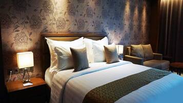 A hotel room with a large bed, two bedside tables, a chair, and a lamp.