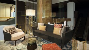A modern living room with a sofa, armchair, and ottoman, a coffee table, and a tall floor lamp. - The Excelton Hotel (Palembang)
