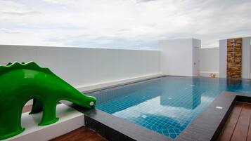 Relax by the pool with a clear view of the sky above, surrounded by a dark tiled edge and a wooden floor.