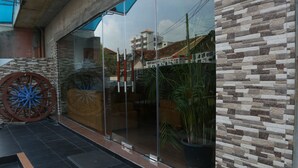 A modern building entrance with a glass door, a large decorative wheel, and a stone wall. - Hotel Eurolanka Colombo (Colombo)